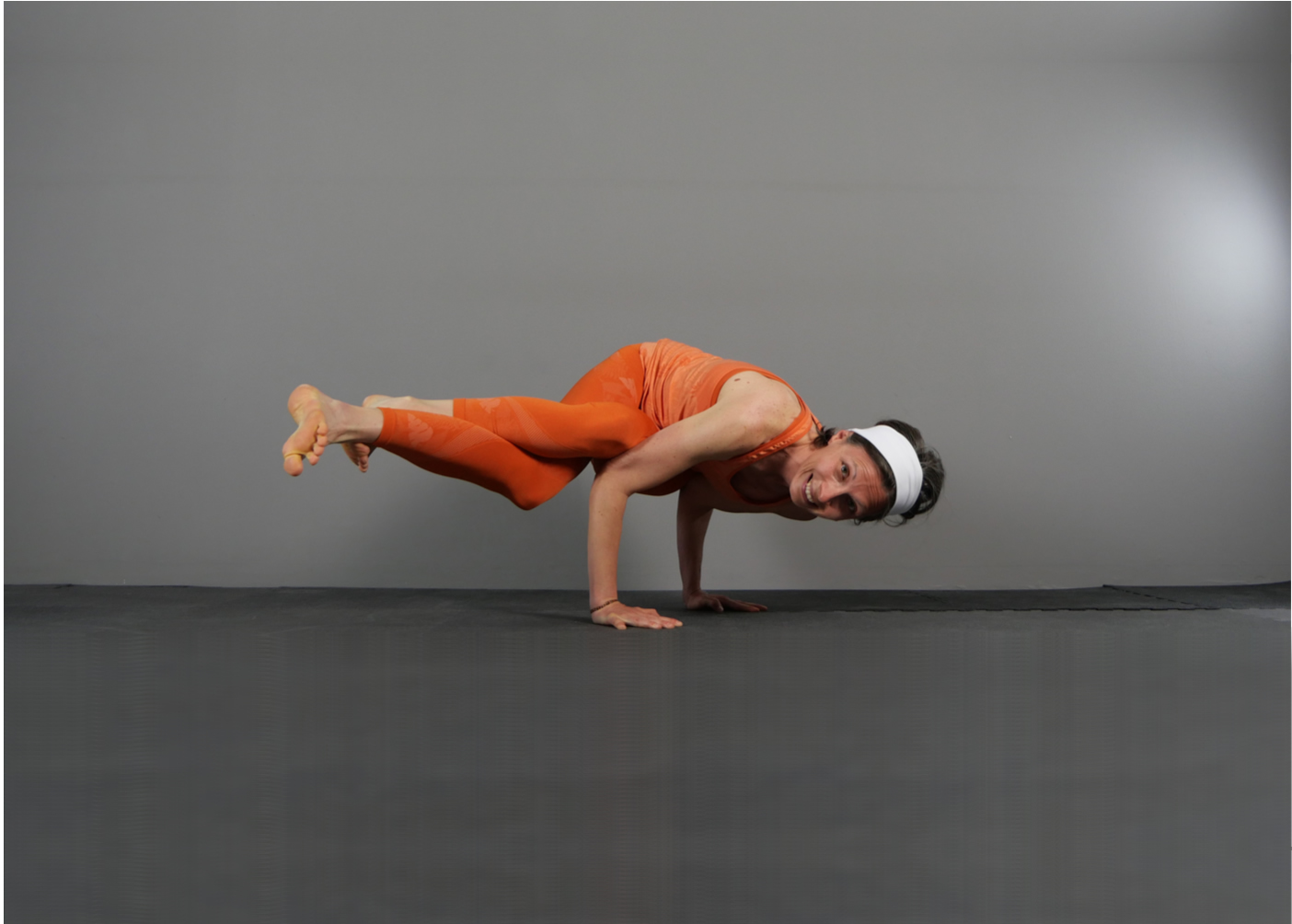 Elisabetta Baso durante i suoi corsi di yoga a padova esegue un’asana, posizione yoga, variante di Parsva Bakasana, con le gambe accavallate come in Garudasana, entrambe le braccia piegate ad angolo retto come in Chaturanga Dandasana, il capo ruotato